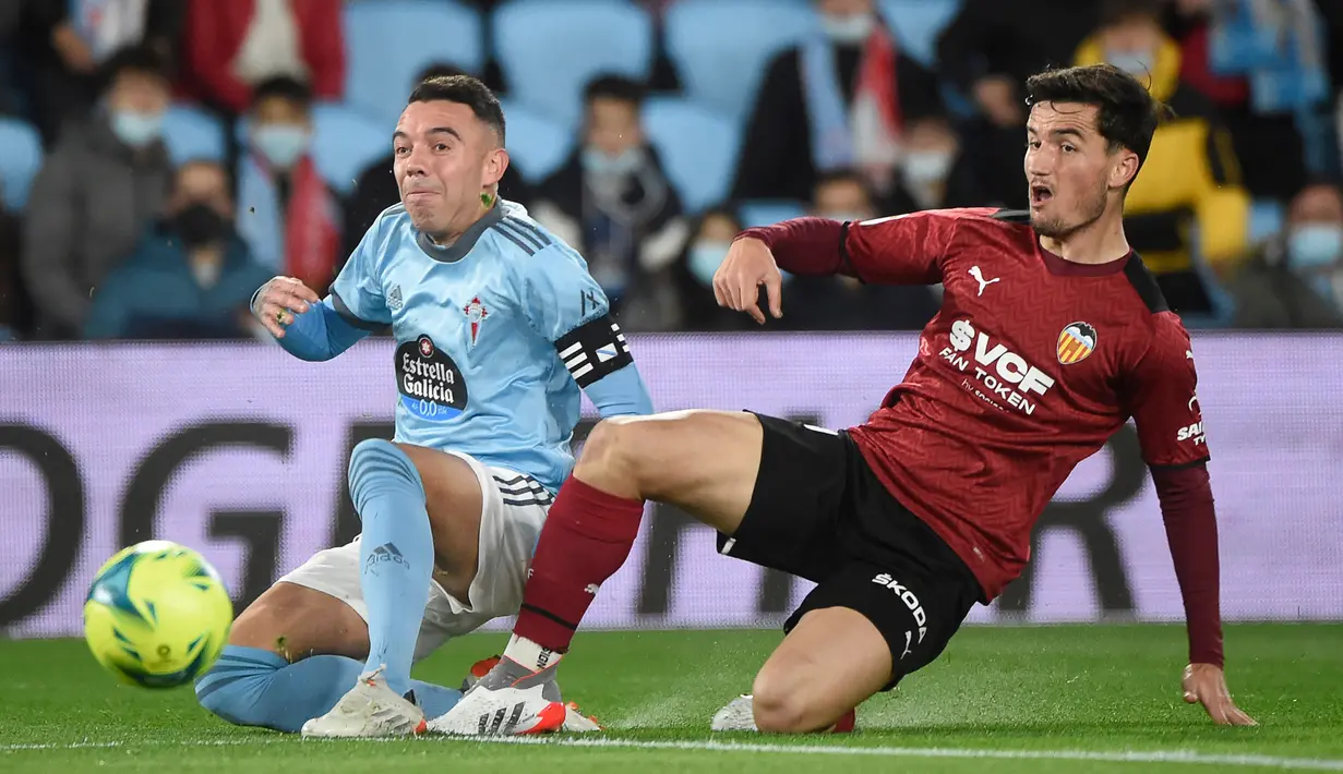 Pemain Celta Vigo Iago Aspas (kiri) menendang bola di sebelah pemain Valencia Hugo Guillamon pada pertandingan Liga Spanyol di Stadion Balaidos, Vigo, Spanyol, 5 Desember 2021. Valencia menang 2-1. (MIGUEL RIOPA/AFP)