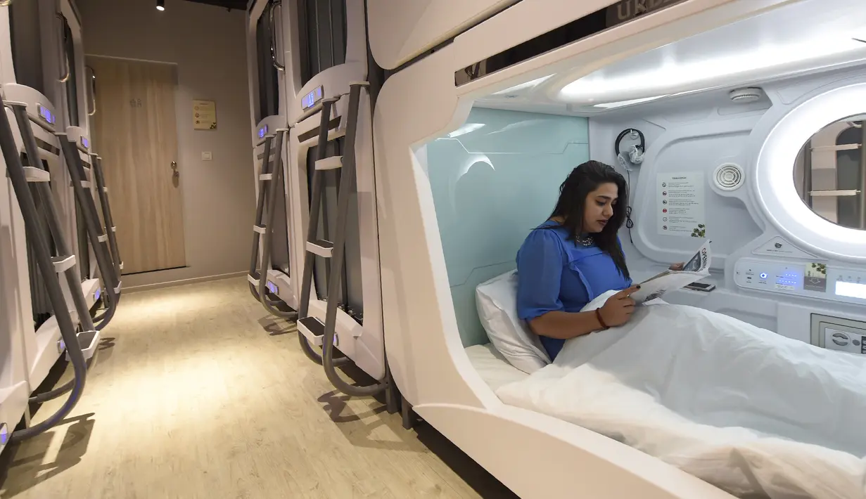 Seorang pengunjung membaca majalah di dalam Hotel Urbanpod di Mumbai, India (14/4). Kapsul hotel di Mumbai ini adalah yang pertama di India. (AFP/Indranil Mukherjee)