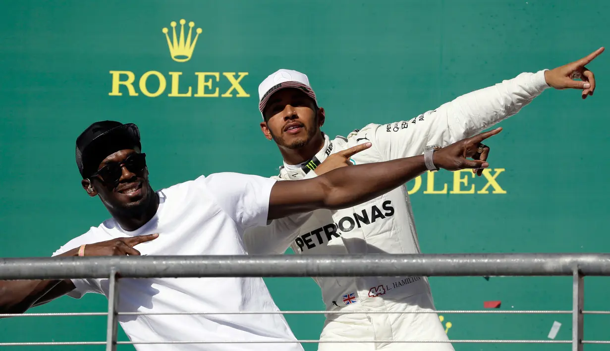 Pembalap asal Inggris dari tim Marcedes, Lewis Hamilton berpose dengan mantan atlet lari cepat asal Jamaika, Usain Bolt di atas podium setelah berhasil memenangi balapan GP Amerika Serikat di Circuit of Americas, Minggu (22/10). (AP Photo/Tony Gutierrez)