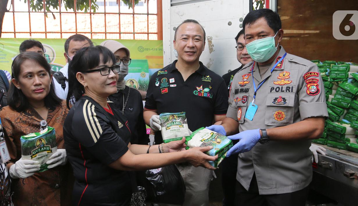 Kapolda Metro Jaya Irjen Nana Sudjana (kanan) disaksikan Direktur Sugar Group Companies Irwan Ang (tengah) secara simbolis memberikan gula pasir kepada warga saat Operasi Pasar di Pasar Palmerah, Jakarta, Jumat (20/3/2020). (Liputan6.com/Fery Pradolo)