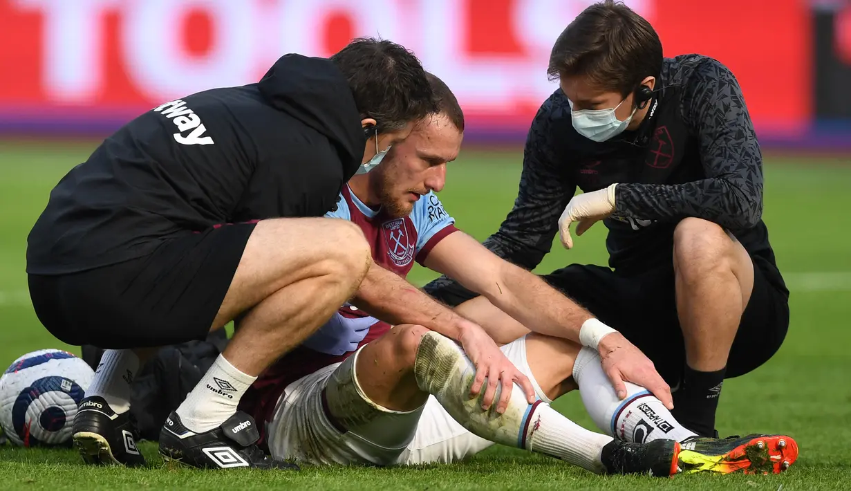 Bek West Ham United, Vladimir Coufal mendapat perawatan usai berbenturan dengan kiper Lukasz Fabianski saat menghadapi Tottenham Hotspur dalam laga lanjutan Liga Inggris 2020/21 pekan ke-25 di The London Stadium, Minggu (21/2/2021). West Ham menang 2-1 atas Tottenham. (AFP/Neil Hall/Pool)