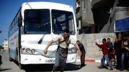 Mohamed Barka, pria yang dijuluki "Super Hero" asal Palestina menarik sebuah bus dengan tali yang terikat di tubuh dalam aksinya di Deir Al-Balah, Gaza Tengah, Kamis (4/2). (MOHAMMED ABED/AFP)