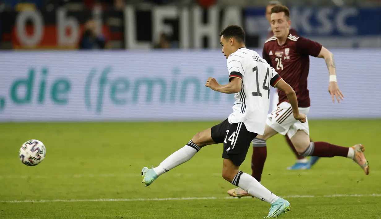 Gelandang timnas Jerman, Jamal Musiala (kiri) berebut bola dengan gelandang Latvia, Aleksejs Saveljevs dalam laga uji coba jelang EURO 2020 di Merkur Spiel Arena, Selasa (8/6/2021) dini hari WIB. Timnas Jerman memenangkan pertandingan dengan skor 7-1 atas timnas Latvia. (Odd ANDERSEN / AFP)