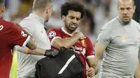 Striker Liverpool, Mohamed Salah, memegang bahu nya saat ditarik keluar lapangan pada laga final Liga Champions di Stadion NSC Olimpiyskiy, Kiev, Minggu (27/5/2018). Salah mengalami cedera bahu usai dilanggar Ramos. (AP/Matthias Schrader)