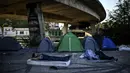 Seorang pencari suaka asal Afghanistan tidur di luar kamp darurat di sebuah kamp migran darurat yang terletak di bawah jembatan jalan raya A1 di utara pinggiran Kota Paris Saint-Denis di Prancis (16/9/2020). (AFP/Christophe Archambault)