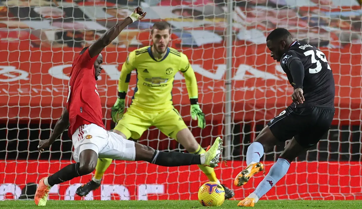 Striker Aston Villa, Keinan Davis (kanan) melepaskan tendangan yang berhasil diblok bek Manchester United, Eric Bailly dalam laga lanjutan Liga Inggris 2020/21 pekan ke-17 di Old Trafford, Jumat (1/1/2021). Aston Villa kalah 1-2 dari Manchester United. (AFP/Carl Recine/Pool)