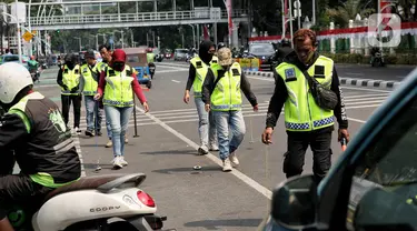 Relawan dari komunitas sapu bersih (saber) ranjau paku menyisir rute yang akan dilewati Pemimpin Gereja Katolik Dunia Paus Fransiskus, Rabu (4/9/2024). (Liputan6.com/Angga Yuniar)