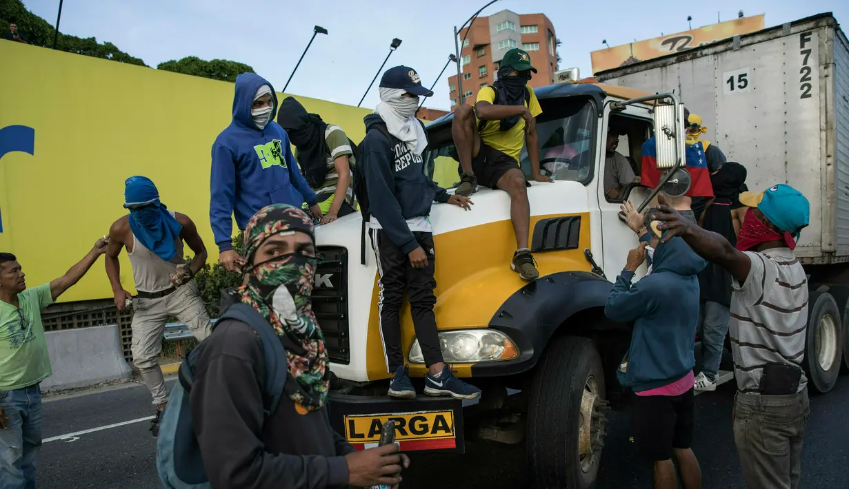 Demonstran antipemerintah membajak sebuah truk saat menuntut pengunduran diri Presiden Nicolas Maduro di Caracas, Venezuela, Sabtu (2/2). (AP Photo/Rodrigo Abd)