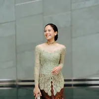 Jadi bridesmaid, Maudy Ayunda tampil ayu dengan kebaya sabrina hijau sage. Dipadukan dengan rok batik cokelat dan clutch silver yang mencolok. [@maudyayunda]