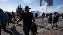 Imigran menghindari gas air mata di dekat pagar pembatas antara Meksiko dan AS di Tijuana, Meksiko (25/11). Walikota Tijuana meminta bantuan PBB untuk menangani sekitar 5.000 migran Amerika Tengah yang telah tiba di kota. (AFP Photo/Guillermo Arias)