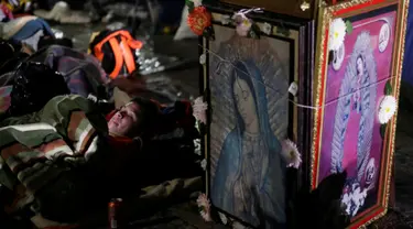 Seorang peziarah beristirahat di samping gambar Bunda dari Guadalupe di kawasan Basilika Guadalupe di Mexico City, Meksiko (11/12). Bunda dari Guadalupe dikenal juga dengan sebutan Our Lady of Guadalupe atau Virgin of Guadalupe. (Reuters/Henry Romero)