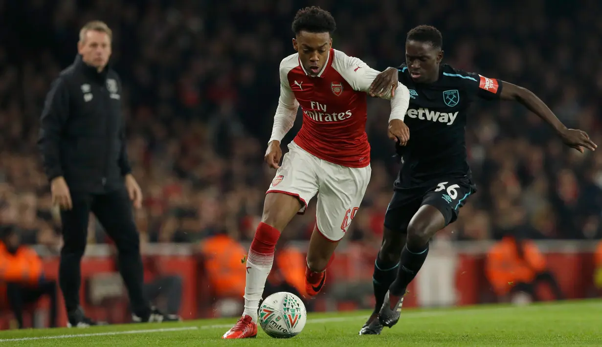 Pemain Arsenal,  Joe Willock berebut bola dengan pemain West Ham, Domingos Quina dalam lanjutan pertandingan Liga Inggris di Stadion Emirates, Minggu (22/4). Arsenal mampu unggul telak dengan skor 4-1. (AP/Alastair Grant)