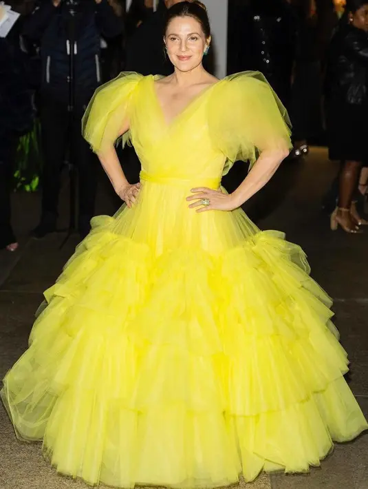 Drew Barrymore terlihat stunning dalam balutan yellow ballgown dari Christian Siriano. Aktris 46 tahun itu melengkapi tampilan dengan anting-anting aqua cerah dan cincin berlian, keduanya oleh Lorraine Schwartz. (Instagram/cfda).