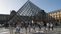 Pengunjung mengentre di piramida Louvre yang dirancang arsitek China Ieoh Ming Pei, pintu masuk ke Museum Louvre pada hari pertama pembukaan di Paris (6/7/2020). Setelah berbulan-bulan ditutup akibat lockdown Covid-19, Museum Louvre kembali dibuka pada 6 Juli 2020. (AFP/Francois Guillot)
