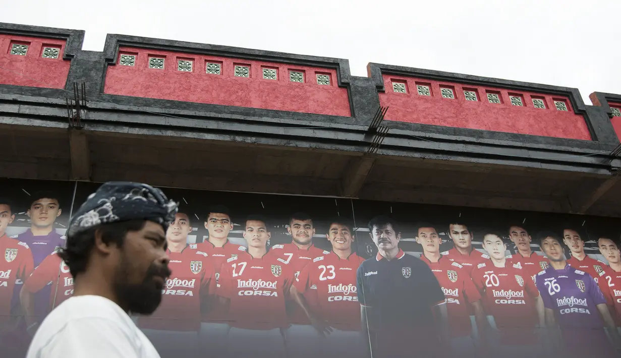 Seorang warga melintasi poster pelatih dan pemain dari Bali United yang terpajang di depan Stadion I Wayan Dipta, Gianyar, Bali, Kamis (3/9/2015). (Bola.com/Vitalis Yogi Trisna)