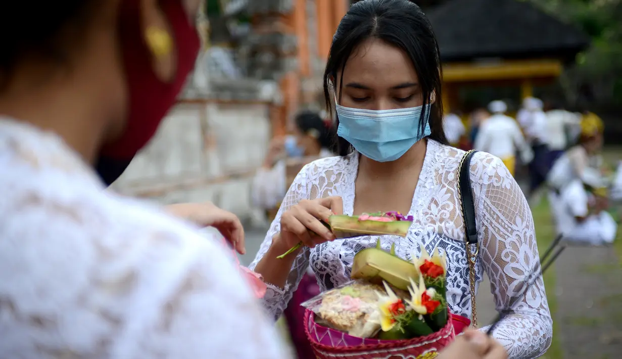 Seorang wanita hindu bersiap berdoa untuk merayakan festival keagamaan Galungan di Pura Jagat Natha di Denpasar, di pulau Bali (16/9/2020). Galungan dirayakan umat Hindu di Bali sebagai hari kemenangan Dharma (Kebaikan) melawan Adharma (Keburukan). (AFP Photo/Sonny Tumbelaka)