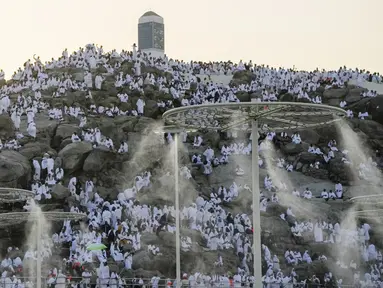 Kabut air disemprotkan ke jemaah haji saat mereka berdoa di bukit berbatu yang dikenal sebagai Gunung Rahmat di Dataran Arafah selama ibadah haji tahunan dekat Kota Suci Makkah, Arab Saudi, Selasa (27/6/2023). Sekitar dua juta jemaah berkumpul di Kota Suci Makkah untuk haji terbesar sejak pandemi virus corona COVID-19 yang sangat membatasi akses ke salah satu dari lima rukun Islam tersebut. (AP Photo/Amr Nabil)