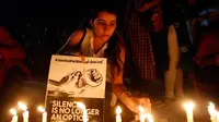 Seorang wanita India menyalakan lilin saat menggelar aksi protes kasus perkosaan di Ahmadabad, India (16/4). Selain itu dipicu juga oleh kasus penculikan serta pemerkosaan seorang gadis remaja di negara bagian utara Uttar Pradesh.(AP Photo / Ajit Solanki)