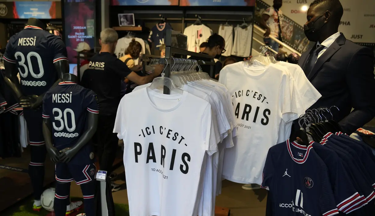 Jersey bertuliskan nama Lionel Messi tergantung dengan beberapa tulisan "Here it's Paris" di toko resmi PSG, di Paris, Rabu (11/8/2021). Penjualan jersey PSG dengan nama Messi dan nomor punggung 30 laris manis, bahkan fans rela antre panjang. (AP Photo/Francois Mori)