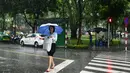 Seorang wanita melintasi jalan saat hujan lebat di Hanoi (14/10/2020). Badai tropis Nangka menghantam Vietnam tengah-utara yang mengakibatkan bencana alam, terutama hujan lebat dan banjir, telah menyebabkan 28 orang tewas dan 12 lainnya hilang. (AFP Photo/Manan Vatsyayana)