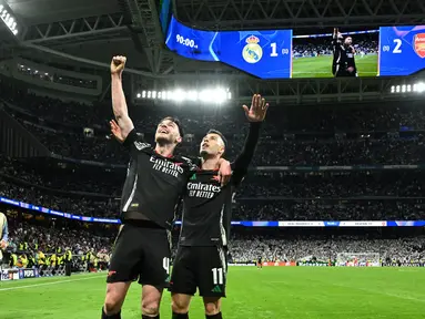 Pemain Arsenal, Gabriel Martinelli (kanan) bersama Declan Rice merayakan yang gol kedua bagi timnya saat pertandingan leg kedua perempat final Liga Champions 2024/2025 melawan Real Madrid di Stadion Santiago Bernabeu, Madrid, Spanyol pada 16 April 2025 atau Kamis 17 April 2025 dini hari WIB. (JAVIER SORIANO/AFP)