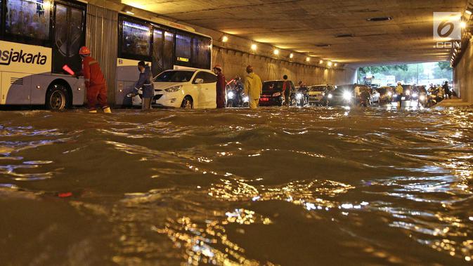 Petugas mengatur arus lalu lintas saat banjir melanda underpass Cawang, Jalan MT Haryono, Jakarta, Selasa (12/12). Hujan deras dan buruknya drainase di kawasan ini menjadi penyebab utama adanya genangan air hingga 50 cm. (Liputan6.com/Herman Zakharia)