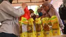 Petugas melayani warga yang membeli minyak goreng seusai mengikuti vaksinasi covid-19 di kawasan Tanah Tinggi, Kota Tangerang, Jumat (4/3/2022). Pemkot Tangerang mengadakan operasi pasar minyak dan daging murah bagi warga yang melaksanakan vaksin covid-19 di lokasi. (Liputan6.com/Angga Yuniar)