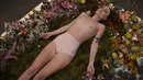 Millie Brown, seorang seniman wanita dalam posisi tidur di atas karya seninya saat pameran berjudul 'Wilting Point' atau Titik Layu di LA Art Show, Los Angeles, Minggu (31/1). Brown akan bertahan selama 5 hari hanya meminum air. (Mark Ralston/AFP)