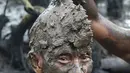 Seorang pria mengambil bagian dalam tradisi mandi lumpur yang dikenal sebagai Mebuug-buugan di Desa Kedonganan, Bali, 4 Maret 2022. Mebuug-buugan diadakan sehari setelah Nyepi yang bertujuan untuk menetralkan sifat buruk. (SONY TUMBELAKA/AFP)