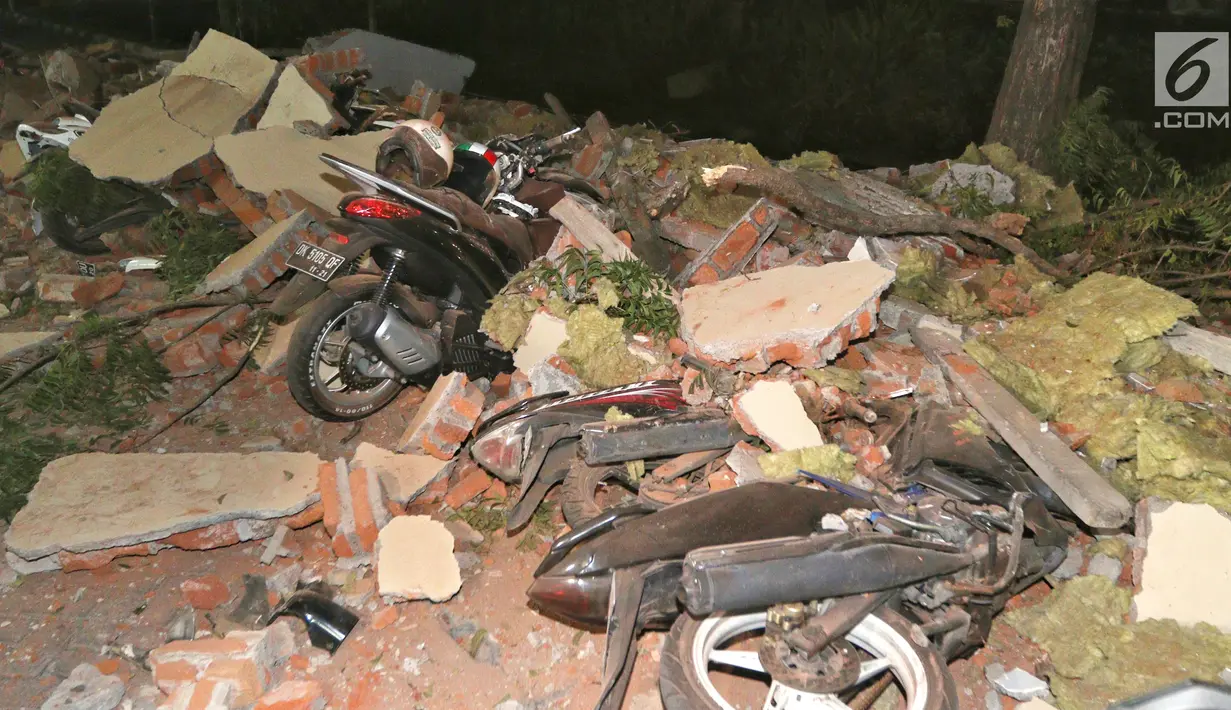 Kendaraan bermotor tertimbun reruntuhan bangunan parkir bertingkat akibat gempa di Mal Galeria, Ngurah Rai, Bali, Minggu malam (5/8). Gempa di Lombok Utara yang berpotensi tsunami telah terdeteksi di Carik pada pukul 18.48 WIB. (Liputan6.com/Johan Tallo)