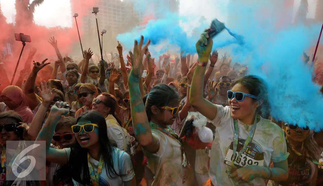 Peserta mengangkat tangan sambil melempar serbuk warna pada puncak event lari santai 5K Colour Run 2016 di Parkir Timur Senayan, Jakarta, Minggu (7/8). Event ini mempromosikan gaya hidup sehat penuh kegembiraan. (Liputan6.com/Helmi Fithriansyah)