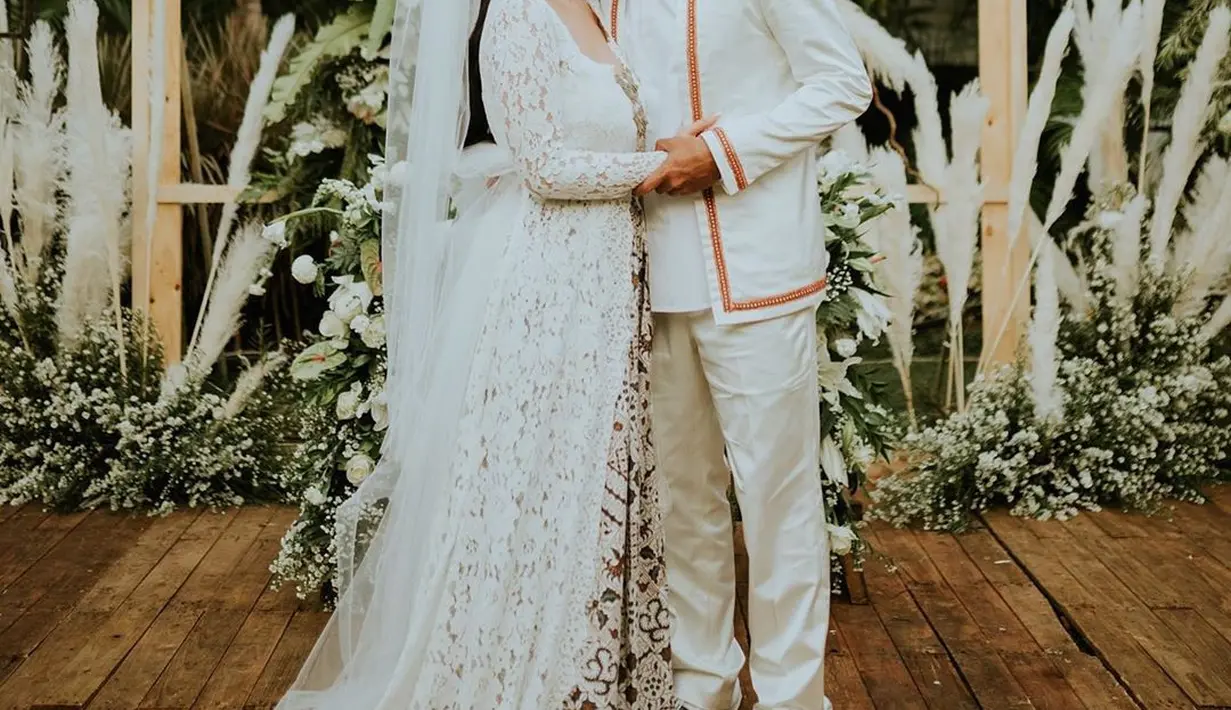 Momen Glenn Fredly mencium mesra istri barunya, Mutia Ayu dengan latar belakang bunga dan dedaunan memperindah foto pernikahan mereka. (Liputan6.com/IG/@mutia_ayuu)