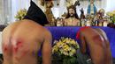 Pria berdoa dengan memakai topeng pada acara kamis putih di kota Mandaluyong, Manila, Filipina, (24/3). Tradisi cambuk merupakan tradisi yang dilakukan oleh beberapa umat Katolik Filipina untuk menyambut hari Paskah. (REUTERS / Romeo Ranoco)