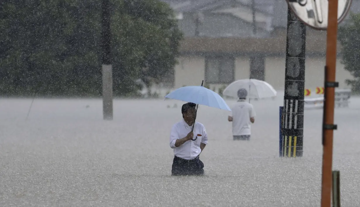 Orang-orang menyeberang jalan akibat hujan lebat di Kurume, Prefektur Fukuoka, Jepang selatan Senin, 10 Juli 2023. (Kyodo News via AP)