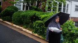 Seorang wanita muslimah berjalan sambil membawa makanan buatannya untuk berbuaka puasa bersama di Dar Al Hijrah Islamic Center, Falls Church, Virginia, AS, 11 Mei 2019. Selain ajang silaturahmi, acara kumpul bersama tersebut diisi dengan pengajian sembari menunggu salat tarawih. (REUTERS/Amr Alfiky)