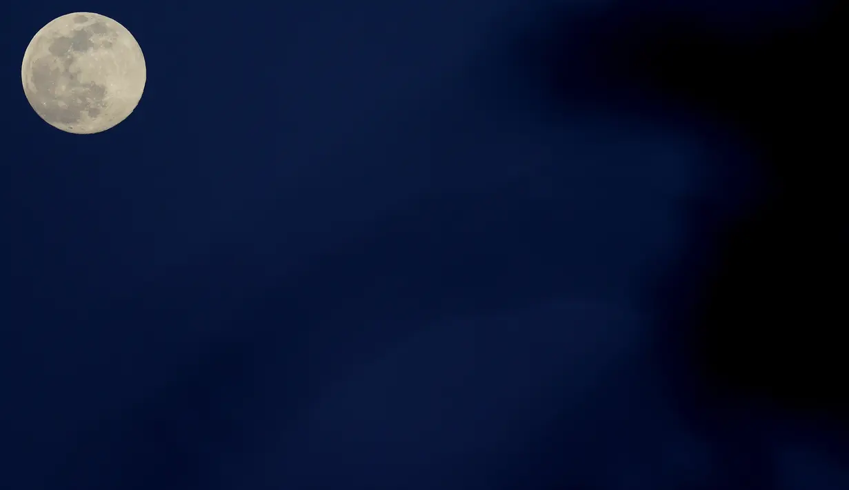 Bulan purnama terbit di atas ibu kota Nicosia di pulau Mediterania timur Siprus, pada Senin (26/4/2021. Bulan purnama di bulan April ini disebut Pink Supermoon lantaran jaraknya dekat dengan perige (garis edar suatu benda langit yang terdekat dengan bumi). (AP Photo/Petros Karadjias)