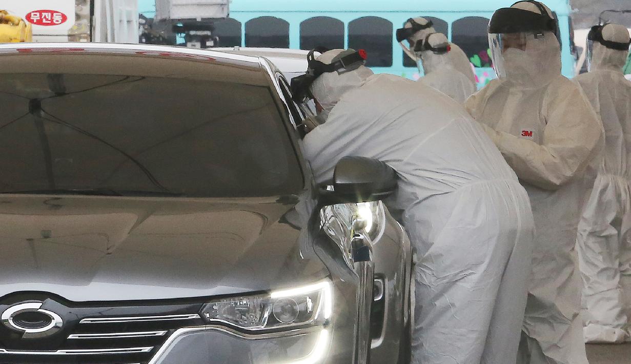 Petugas medis dengan pakaian pelindung mengambil sampel dari pengemudi di layanan "drive-thru" di Goyang,  1 Maret 2020. Untuk mengefisiensi waktu, pemerintah Korea Selatan membuat layanan tes uji virus corona COVID-19 kepada warganya via drive thru (tanpa turun). (AP/Ahn Young-joon)
