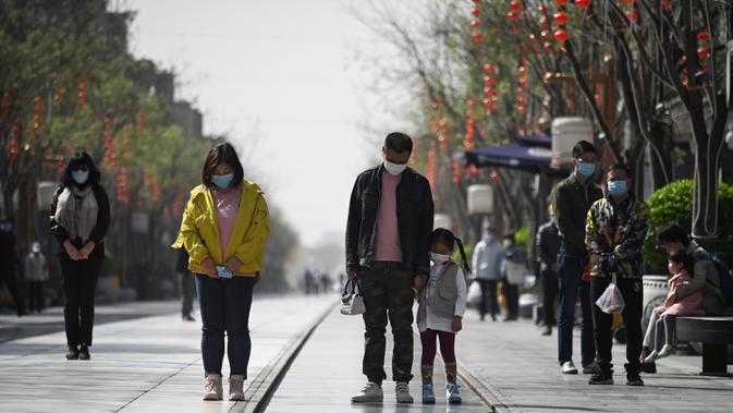 Orang-orang mengenakan masker membungkuk tiga menit selama peringatan nasional untuk memperingati korban meninggal dalam wabah virus coronavirus COVID-19 di sepanjang jalan bisnis di Beijing (4/4/2020). (AFP/Wang Zhao)