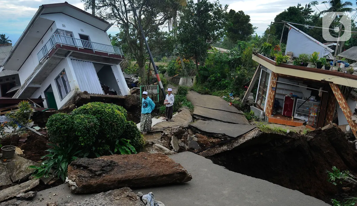 Santri Pesantren Al Burok melintasi jalan yang hancur akibat gempa di , Kampung Cisarua, Desa Sarampad, Cianjur, Jawa Barat, Rabu (21/11/2022). Gempa bumi dengan magnitude 5,6 di Cianjur Jawa Barat yang berpusat di darat 10 km barat daya embuat sejumlah rumah dan bangunan rusak. (merdeka.com/Arie Basuki)