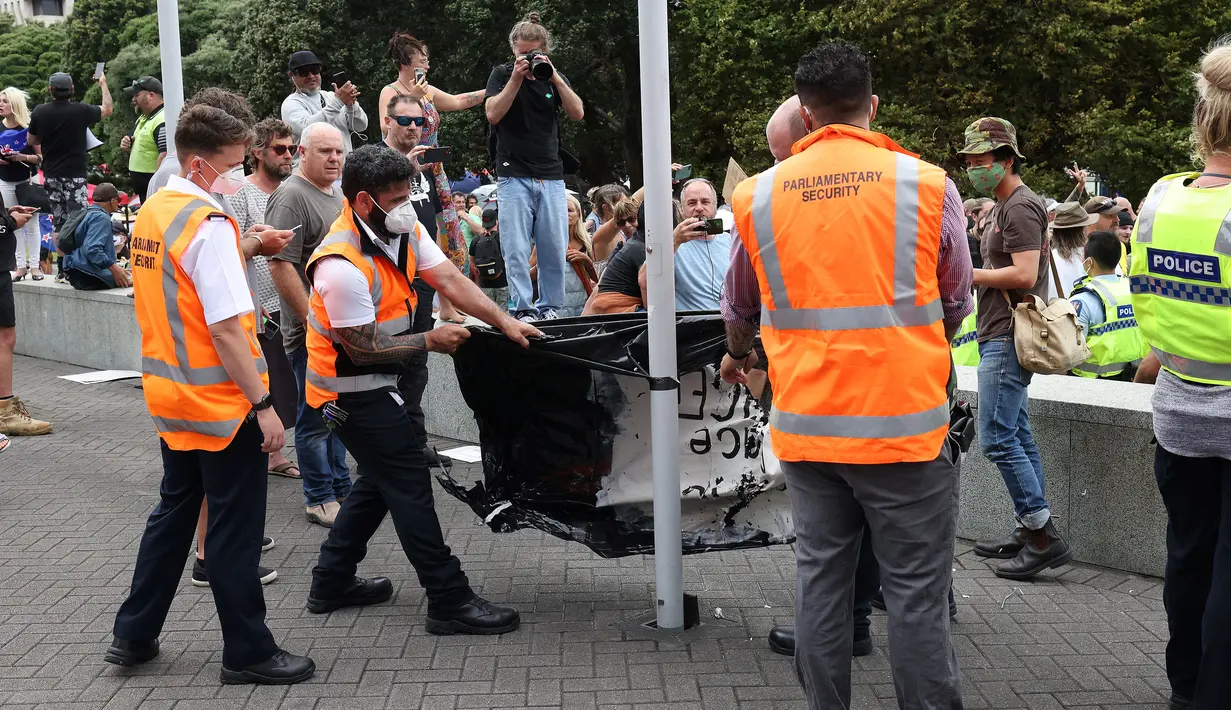 Petugas keamanan parlemen membongkar tenda di halaman parlemen pada hari ketiga demonstrasi menentang pembatasan Covid-19, yang terinspirasi oleh demonstrasi serupa di Kanada, di Wellington (10/2/2022). (AFP/Marty Melville)