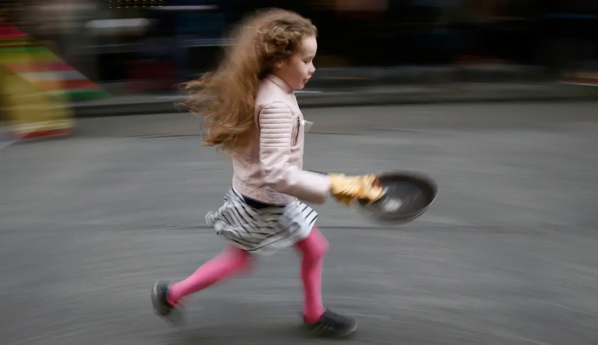 Evie Lloyd (7) ikut ambil bagian dalam acara tahunan Great Spitalfields Pancake Race di London, Inggris, Selasa (9/2). Dalam lomba itu, peserta diwajibkan berlari sambil membalik pancake tanpa membuatnya terjatuh. (REUTERS/Stefan Wermuth)