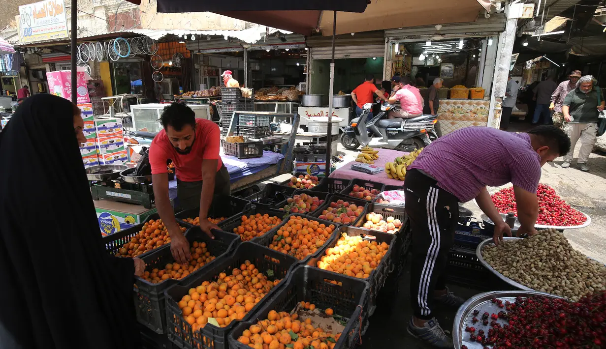 Pedagang buah melayani pembeli selama bulan suci Ramadan di pasar Baghdad (24/5/2019). Baghdad adalah salah satu kota terbesar di dunia dan menjadi rumah bagi umat Muslim, Kristiani, Yahudi dan penganut paganisme dari seluruh Timur Tengah dan Asia Tengah. (AFP Photo/Ahmad Al-Rubaye)