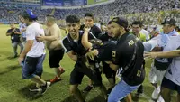Tragedi sepak bola yang melibatkan suporter kembali terjadi. Kali ini 12 orang dilaporkan meninggal dunia dalam sebuah insiden tragis di Stadion Monumental, Cuscatlan, San Salvador, El Salvador, Sabtu (21/5/2023) malam waktu setempat pada laga perempatfinal Divisi Utama El Salvador antara Alianza FC menghadapi Deportivo FAS. Para korban tewas akibat berdesakan saat menyerbu salah satu pintu masuk stadion. Akibat kejadian tersebut, laga pun terpaksa dihentikan setelah terjadi desak-desakan suporter yang meluber hingga ke dalam lapangan. (AP Photo/Milton Flores)