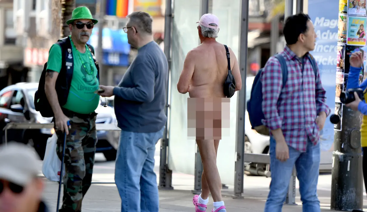 Seorang nudis berjalan melewati kerumunan orang saat mengikuti acara Nude Love Parade di San Francisco, California, AS, Minggu (17/3). Nudis adalah sebutan bagi mereka yang menjalankan tradisi telanjang. (Josh Edelson/AFP)