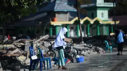 Seorang anak yang terkena dampak gempa meminta sumbangan pada pengguna jalan yang melintas di Donggala, Sulawesi Tengah, Jumat (5/10). Akibat terlambatnya pasokan bantuan, mereka terpaksa meminta sumbangan hingga turun ke jalan. (AFP PHOTO / Jewel SAMAD)