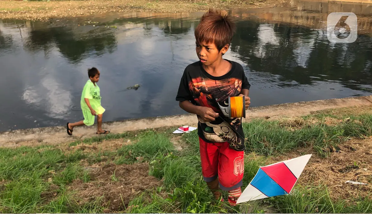 Anak-anak bermain di sekitar bantaran Kanal Banjir Timur (KBT), kawasan Cipinang Muara, Jakarta, Selasa (16/6/2020). Sebagian besar warga masih mengabaikan protokol kesehatan dengan tidak menjaga jarak serta tanpa menggunakan masker. (Liputan6.com/Immanuel Antonius)
