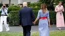 Presiden AS Donald Trump menggandeng tangan istrinya, Melania untuk menyambut keluarga militer pada acara piknik di halaman Gedung Putih, Rabu (4/7). Pasangan yang jarang bergandengan tangan di depan umum itu langsung mencuri perhatian. (AP/Alex Brandon)