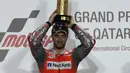 Pembalap Ducati Andrea Dovizioso berpose diatas podium sambil memegang pialanya usai memenangkan balapan di MotoGP Qatar 2018 di Sirkuit Internasional Losail (18/3). (AFP Photo/Karim Jaafar)