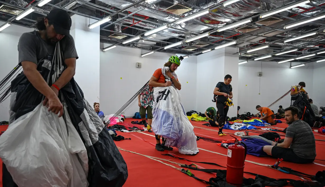 Para penerjun mempersiapkan parasut mereka sebelum melompat dari dek terbuka Menara Kuala Lumpur saat International Tower Jump, Kuala Lumpur, Malaysia, 3 Februari 2023. Lebih dari 100 penerjun melompat dari Menara Kuala Lumpur setinggi 300 meter yang terkenal tersebut. (MOHD RASFAN/AFP)