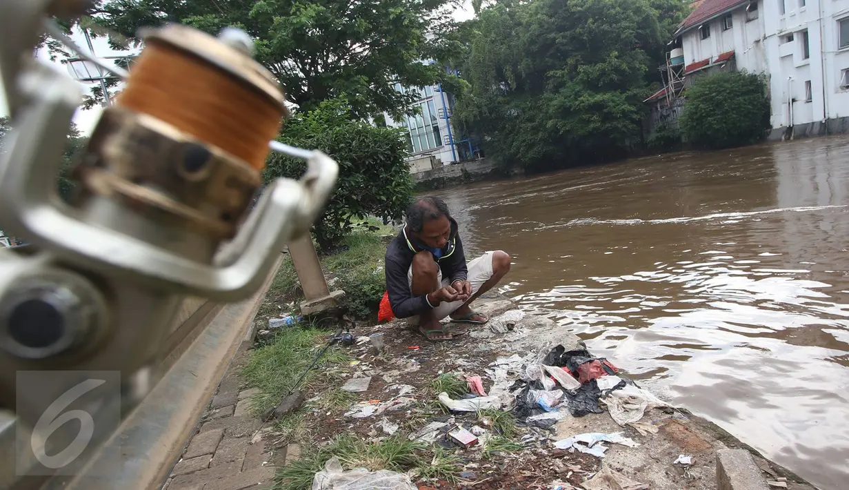 Warga mempersiapkan umpan sebelum memancing di bantaran Sungai Ciliwung, Jakarta, Selasa (21/2). Meluapnya Sungai Ciliwung menjadi berkah tersendiri bagi warga untuk memancing dan menjala ikan yang terbawa arus dari hulu. (Liputan6.com/Immanuel Antonius)